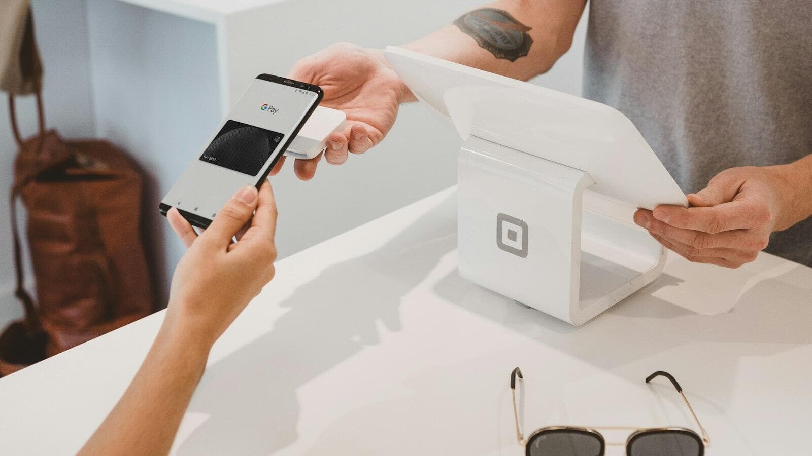 A hand paying with a phone at a card terminal