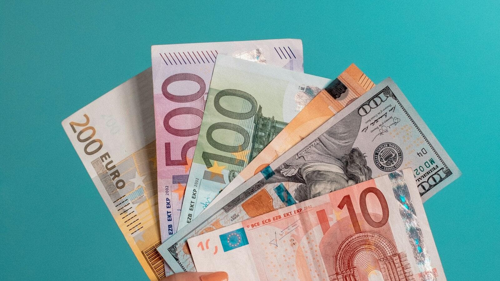 A hand holding a fan of euro banknotes